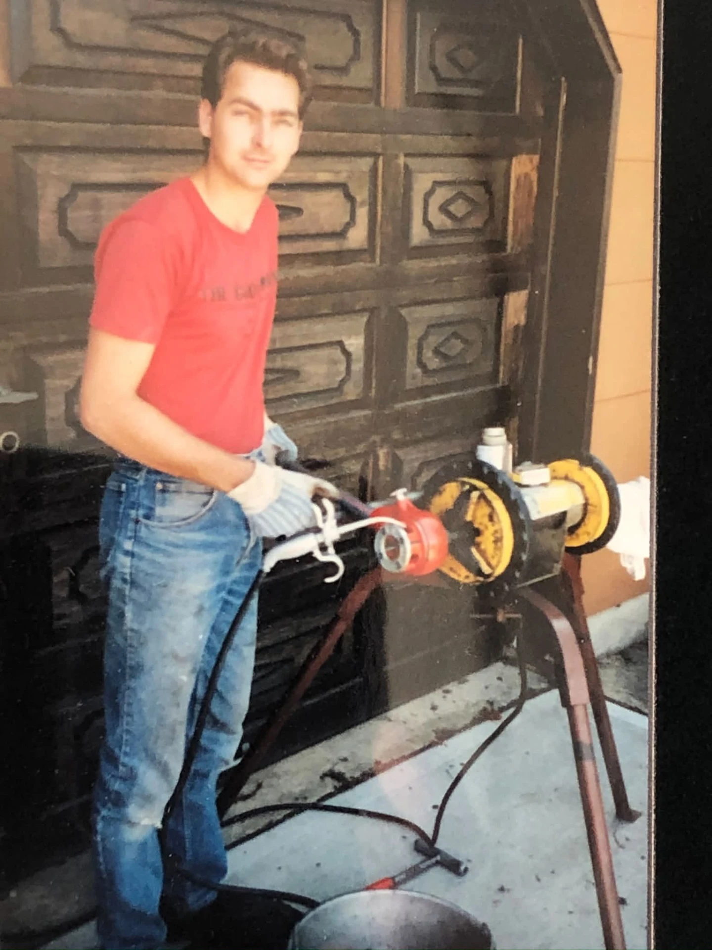A young Tom threading pipe outside a garage